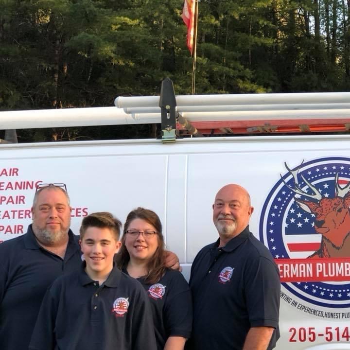Four people in matching shirts stand in front of a work van with the German Plumbing logo and partial phone number visible; trees and an American flag are in the background.